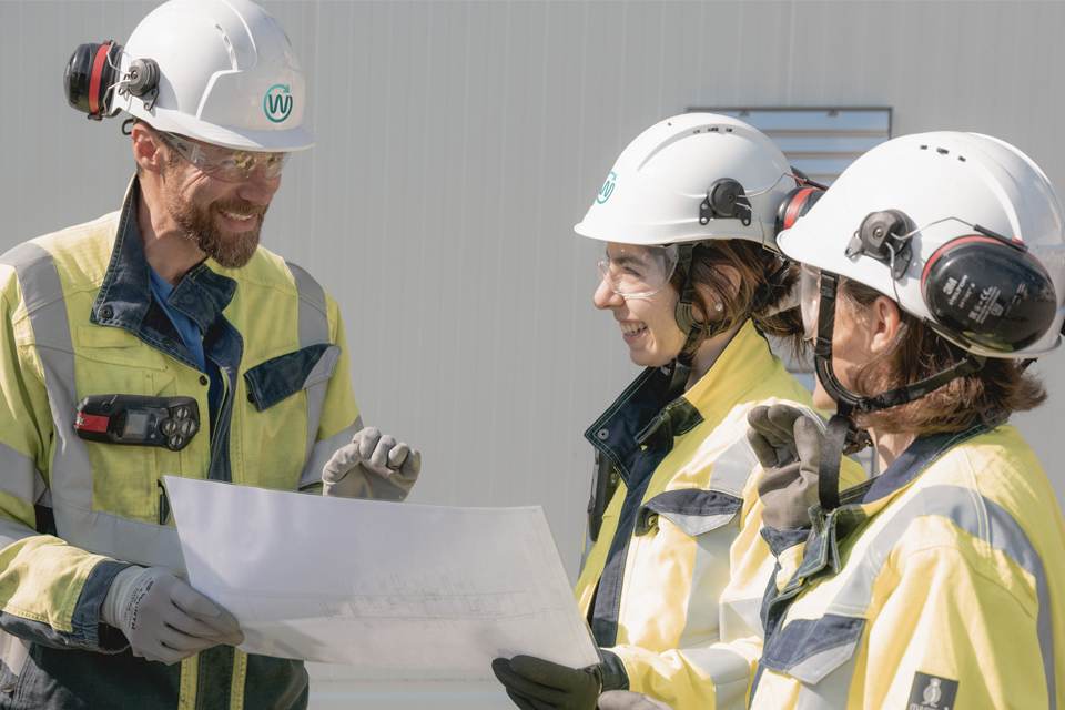 Image représentant trois collaborateurs de Waga Energy devant une unité WAGABOX.